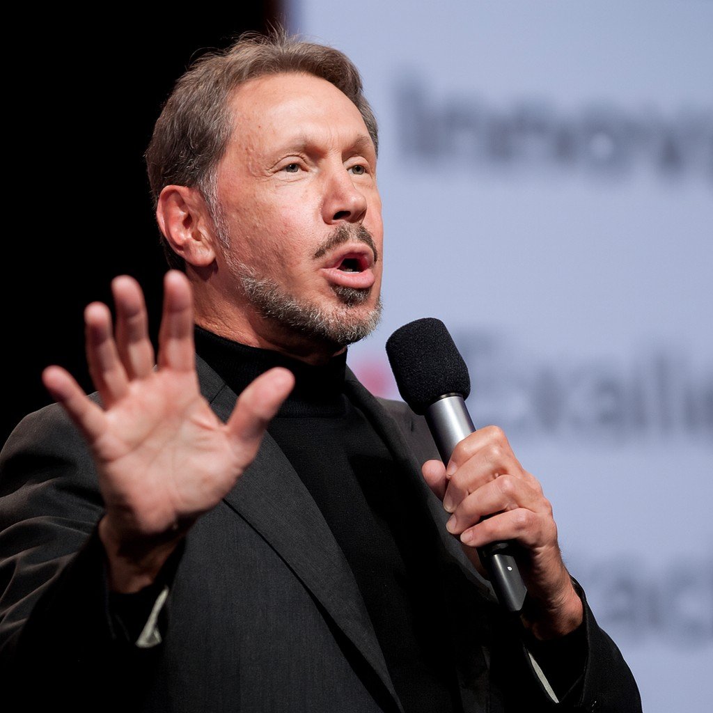 Larry Ellison briefly becomes world’s richest person while speaking at an event, holding a microphone and addressing the audience.