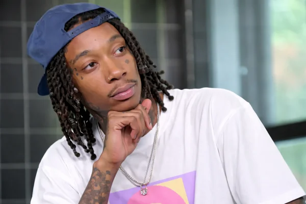 Wiz Khalifa Sentenced in Romania as the rapper appears in a thoughtful seated posture during a studio or interview setting.