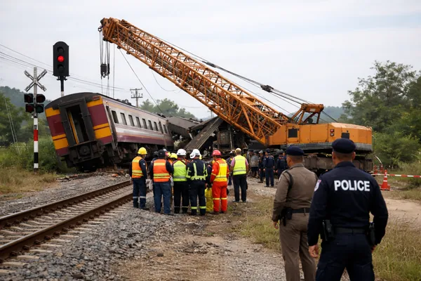 Thailand crane train crash aftermath showing a derailed passenger train and collapsed construction crane in northeastern Thailand as emergency responders coordinate rescue efforts.